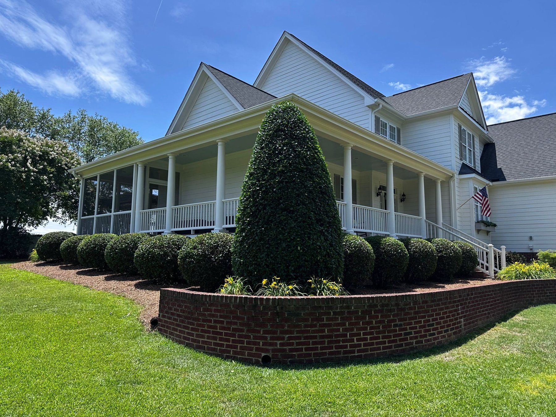 Neatly trimmed hedges and shrubs along a white house